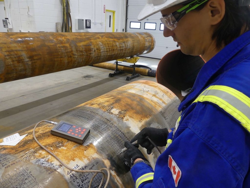 A technician uses specialized equipment to perform hardness testing on a section of pipeline, ensuring material integrity and reliability.